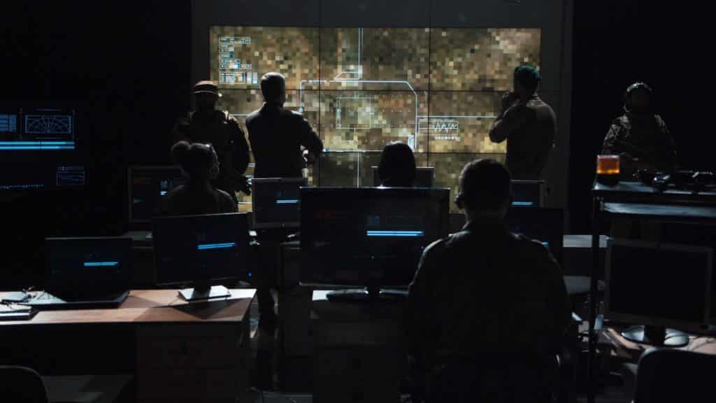 A group of soldiers looking at a digital map in a dark room.