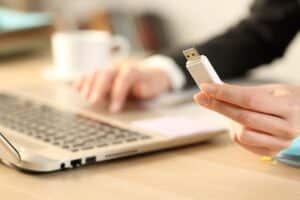 An image of a person contemplating plugging a USB stick into a laptop as a representation of USB allowlisting